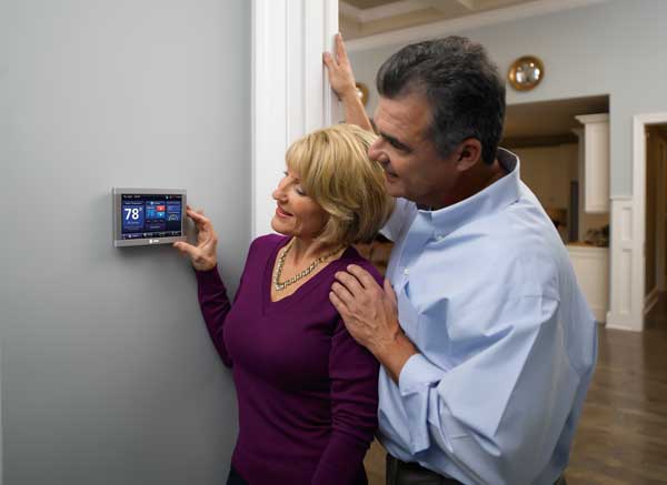 Man and woman adjusting thermostat on wall set at 78 degrees